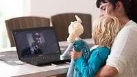 Frau und Kind sitzen vor Laptop