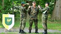 Drei Soldaten: Die zwei außenstehenden legen dem in der Mitte neue Dienstgradabzeichen auf.