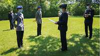 Mehrere Soldatinnen und Soldaten stehen mit Mund-Nase-Schutz auf einer Wiese