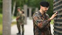 Ein Soldat berührt eine Namensstele im „Wald der Erinnerung“.