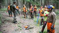 Soldaten mit Schutzausrüstung stehen in einem Kreis im Wald zusammen