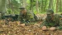 Zwei Soldaten liegen auf dem Waldboden und beobachten in Feindrichtung.