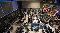 In einem großen Raum arbeiten viele Soldatinnen und Soldaten unterschiedlicher Nationen an Computern