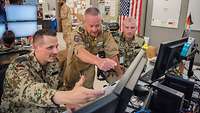 Drei Soldaten schauen auf einen Monitor und bewerten die Aufklärungsbilder