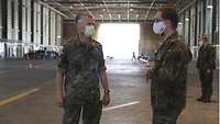 Zwei Soldaten stehen in der Drive-Through-Station im Hangar und unterhalten sich.