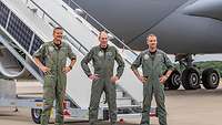 Drei Soldaten stehen vor einer Flugzeugtreppe. 