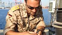 Ein Soldat hält ein Netzwerkkabel in den Händen und verbindet es mit einem anderen