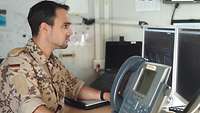 Ein Soldat sitzt vor einem Monitor und bedient eine Computermaus