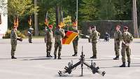 Ein Soldat befestigt das Fahnenband an der neuen Truppenfahne.