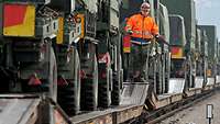 Militärische Fahrzeuge werden auf Bahnflachwagen verladen.