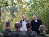 Ein katholischer und evangelischer Miilitärpfarrer halten einen Feldgottesdienst vor einer Gruppe von Soldaten