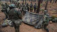 Bundeswehrsoldaten bauen im Wald ein Zelt auf