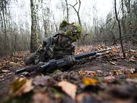 Ein Bundeswehrsoldat gleitet mit dem Gewehr G36 über den Waldboden