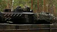 Ein Panzer mit geöffneter luke steht im Wald