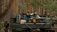 Soldaten reichen Patronen für die Bordkanone von einem Lkw zu einem Panzer herüber