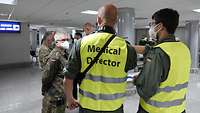 Mehrere Soldaten unterhalten sich, eine trägt eine Signalweste mit der Aufschrift Medical Director