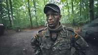 Porträt eines Soldaten mit Tarnschminke im Gesicht im Laubwald.