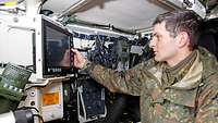 Ein Soldat bedient eine computergestützte Anlage im Inneren des Panzers