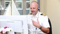 Das Bild zeigt Kapitän zur See Panke vor einem Bildschirm und mit Headset bei einer Online-Beratung
