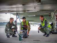 Ein britischer und zwei deutsche Techniker in einer Besprechung unter einem Eurofighter auf dem Flugplatz in Ämari.