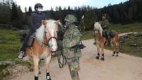 Eine Frau sitzt auf einem Haflinger. Ein Soldat mit einer umgehängten Waffe steht neben dem Tier.