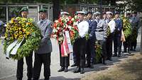 Soldaten aller Truppengattungen tragen die Kränze in zweier Reihe zum Gedenkstein Henning von Tresckows