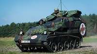 Driver and commander observe from a small tracked vehicle.