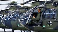 A training helicopter with an open cockpit door. A pilot sits in the cockpit, smiling at the camera.