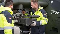 Three technicians mount the heavy machine gun on the Tiger weapon pylon.