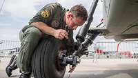 A technician checks the wheel suspension system of a parking helicopter.