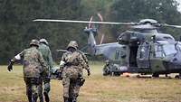 Four soldiers carry a patient to a waiting helicopter.