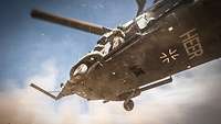 View of the underside of a landing helicopter. Dust swirls.