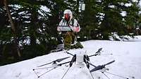 A soldier in snow camouflage launches the MIKADO drone from the ground.