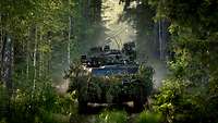 A reconnaissance patrol moves in its reconnaissance vehicle through a woodland area.