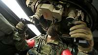 A soldier sits in a Fennek reconnaissance vehicle and operates the weapon system.