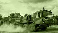 Raising a cloud of dust, a heavy equipment transporter carries a Fuchs armoured transport vehicle.