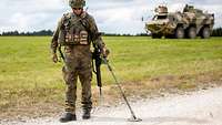 An engineer uses a metal detector to scan a road.