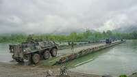 A Fuchs armoured transport vehicle uses a ribbon bridge to cross a river.