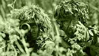 The image shows two armed infantry soldiers: A platoon leader is giving instructions to a soldier.