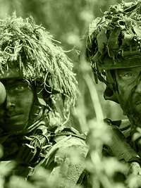 The image shows two armed infantry soldiers: A platoon leader is giving instructions to a soldier.