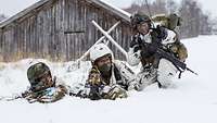 Three infantry soldiers are in position in the snow.