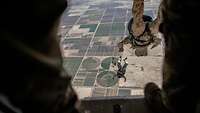 Soldiers jump headfirst from an aircraft.