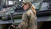Eine Soldatin vor einem Fahrzeug