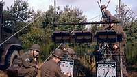 Five soldiers setting up a communication system outdoors. 