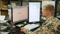 Ein Soldat sitzt am Schreitisch und arbeitet am Computer