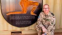 Hauptmann Hendrik M. kniet vor seinem Wappen Einsatzzug Mantis