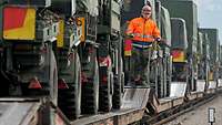 Militärische Fahrzeuge werden auf Bahnflachwagen verladen.