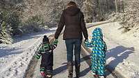 Eine Frau und zwei Kinder spazieren im Schnee