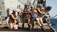 Vier Soldaten mit Sicherheitsgeschirr holen die Arbeitsleine zwischen den Schiffen über