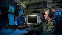 Zwei Soldatinnen sitzen im DCRC vor einer Wand aus Bildschirmen und beobachten die Luftlage über dem Baltikum.